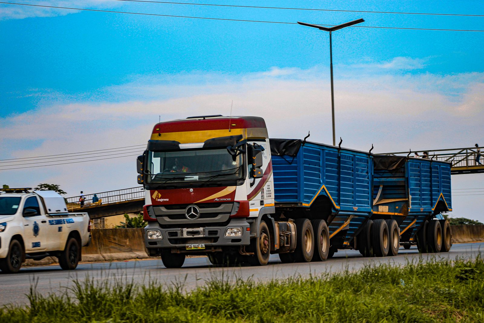 Truck pulling blue double side-tipper trailers on a highway